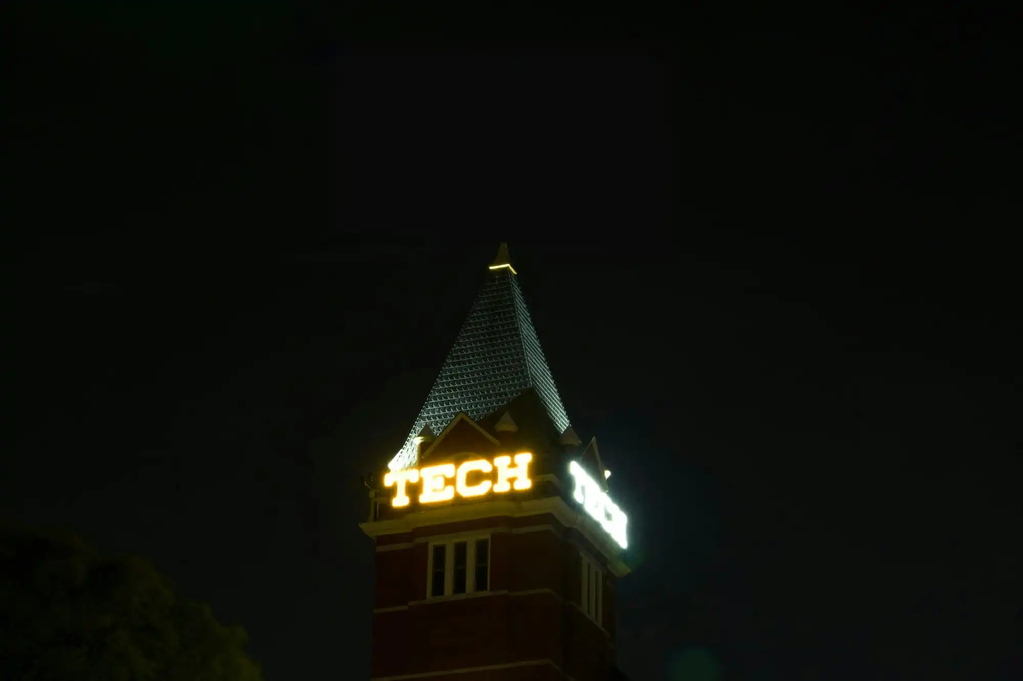Tech Tower at Georgia Tech at night, its lit TECH sign below a dark spire.